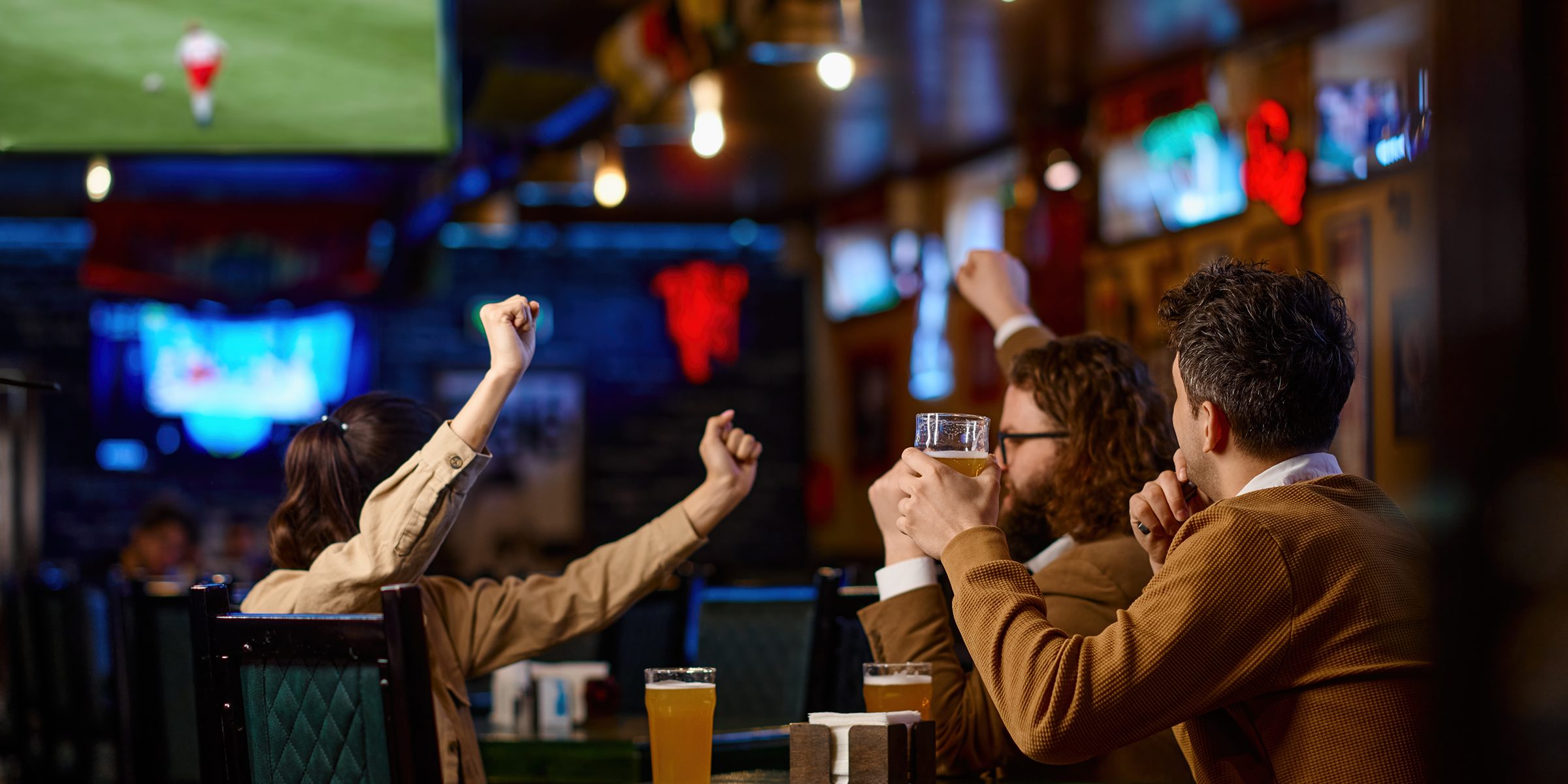 Close-up of friends group toasting with beer while sitting in beer pub together